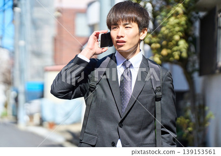 一位年輕的日本商人外出拜訪客戶時,在街上接了電話。 一位年輕的日本商人外出拜訪客戶時,在街上接了電話。 139153561