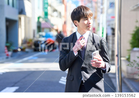 一位年輕的日本商人外出拜訪客戶時,在街上接了電話。 一位年輕的日本商人外出拜訪客戶時,在街上接了電話。 139153562
