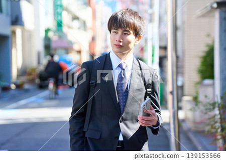 一位年輕的日本商人外出拜訪客戶時,在街上接了電話。 一位年輕的日本商人外出拜訪客戶時,在街上接了電話。 139153566