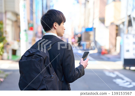 一位年輕的日本商人外出拜訪客戶時，在街上接了電話。 139153567