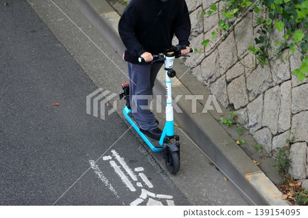 An electric kick scooter running on the road 139154095