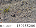 SOS and a small flower written in the sand 139155200