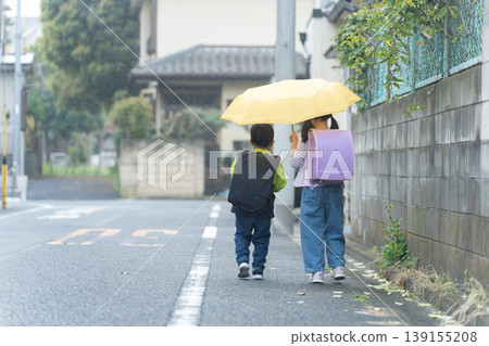 Elementary school students walking to and from school with their backpacks on on a rainy day. Elementary school students walking to and from school with their backpacks on on a rainy day. 139155208