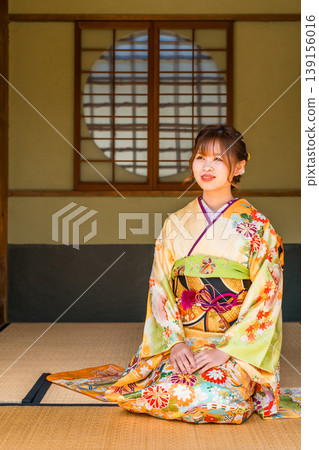 一位穿著振袖和服的日本年輕女子坐在日式房間的榻榻米上（成年禮，20歲生日慶祝活動）。 139156016