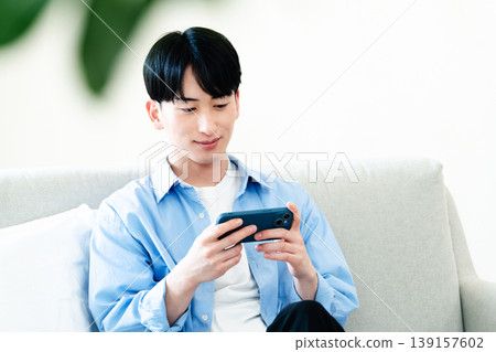 A man who uses a smartphone in the living room A man who uses a smartphone in the living room 139157602