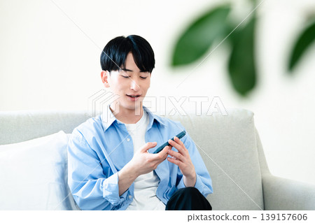A man who uses a smartphone in the living room A man who uses a smartphone in the living room 139157606