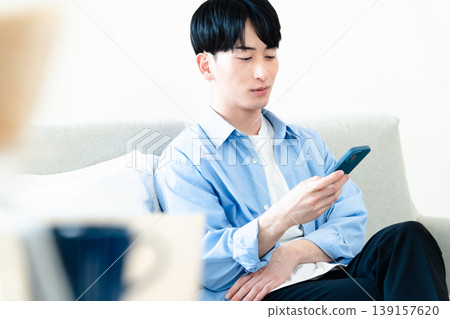 一個在客廳裡使用智能手機的人 139157620