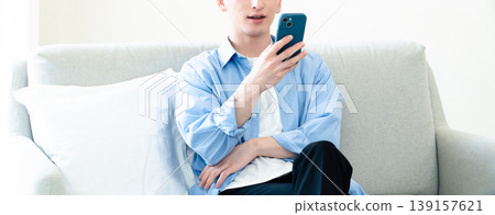 A man who uses a smartphone in the living room A man who uses a smartphone in the living room 139157621