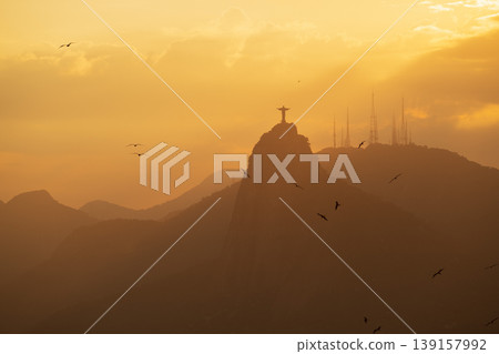 Serene golden sunset silhouette of Christ Redeemer on Corcovado mountain famous landmark in Rio de Janeiro Brazil Serene golden sunset silhouette of Christ Redeemer on Corcovado mountain famous landmark in Rio de Janeiro Brazil 139157992