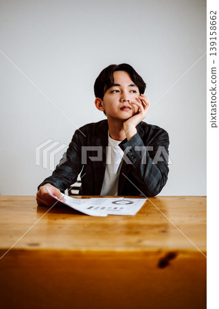 A man thinking while looking at documents A man thinking while looking at documents 139158662