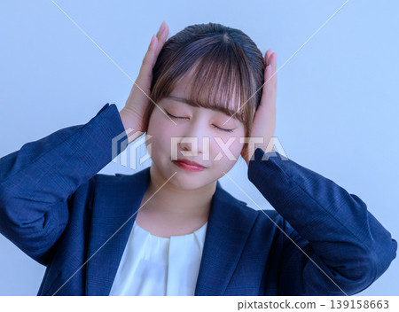 A woman in a suit covering her ears. A woman in a suit covering her ears. 139158663