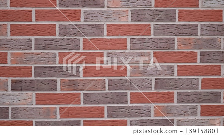 Brickwork made of multi-colored bricks with smooth seams and empty space on the textured surface, a wall made of gray, red and brown bricks, a fragment of the interior used as a background. 139158801