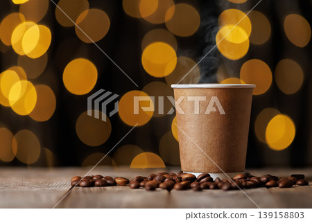 Steaming hot coffee drink in a blank paper cup, surrounded by roasted coffee beans on wooden table, with warm bokeh lights creating cozy atmosphere in the background Steaming hot coffee drink in a blank paper cup, surrounded by roasted coffee beans on wooden table, with warm bokeh lights creating cozy atmosphere in the background 139158803