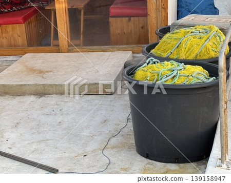 Fishing nets in large black containers on dockside with wooden cabin in background Fishing nets in large black containers on dockside with wooden cabin in background 139158947