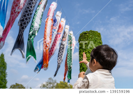 一個孩子伸手去夠一條鯉魚擬餌。 一個孩子伸手去夠一條鯉魚擬餌。 139159196