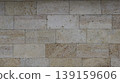 A beautiful texture of glossy finishing stone tiles in a block exterior masonry structure with raindrops on the textured surface of sand-colored natural stone with elegant streaks of rock cut 139159606