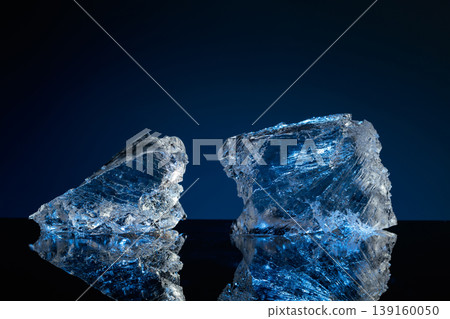 Broken ice with blue backlight on a black reflective background. 139160050