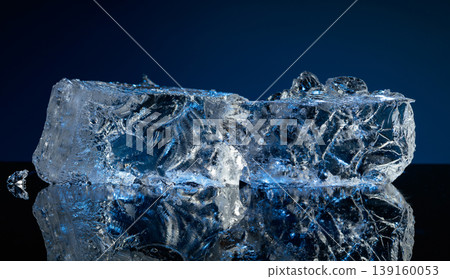 Broken ice with blue backlight on a black reflective background. 139160053