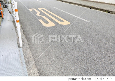 A road with a 30 km/h speed limit. Yellow paint markings. Speed limit sign. Traffic safety. 139160622