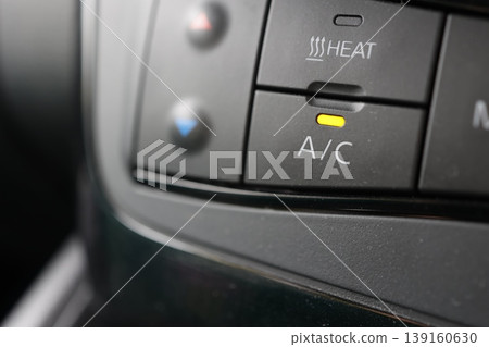 Car air conditioning (A/C) button. Yellow indicator light illuminates. Temperature adjustment. Close-up. Car air conditioning (A/C) button. Yellow indicator light illuminates. Temperature adjustment. Close-up. 139160630