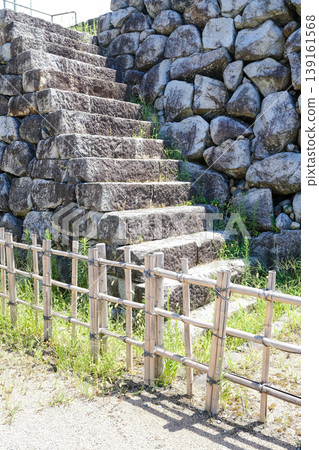 A Japanese garden-style landscape with old stone steps leading along a stone wall and a bamboo fence. A Japanese garden-style landscape with old stone steps leading along a stone wall and a bamboo fence. 139161568