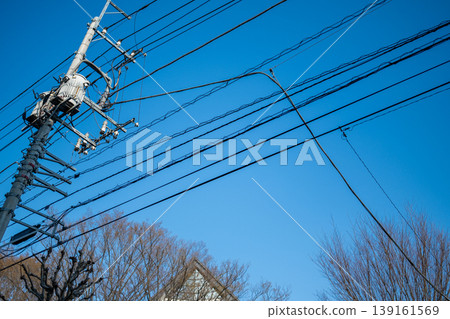 A scene of a Japanese residential area with utility poles and power lines stretching into the blue sky. A scene of a Japanese residential area with utility poles and power lines stretching into the blue sky. 139161569