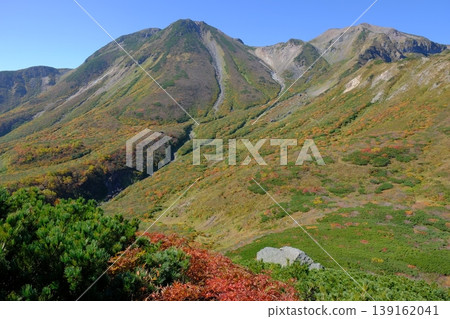 The mountain ridges and peaks of the alpine zone, adorned in autumn colors, and the mountain scenery against a blue sky, with their colorful slopes. The mountain ridges and peaks of the alpine zone, adorned in autumn colors, and the mountain scenery against a blue sky, with their colorful slopes. 139162041