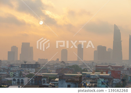 Sunset over a busy city skyline shrouded in haze with tall skyscrapers silhouetted against a warm, glowing sky, urban sunset scene with fuzzy atmosphere Sunset over a busy city skyline shrouded in haze with tall skyscrapers silhouetted against a warm, glowing sky, urban sunset scene with fuzzy atmosphere 139162268