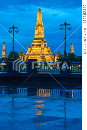 Illuminated Thai Wat Temple at Dusk with Reflection on Wet Ground and Blue Sky Illuminated Thai Wat Temple at Dusk with Reflection on Wet Ground and Blue Sky 139162322