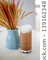 Decorative dried grass arrangement in a pastel blue ceramic vase, close-up of natural dry flowers in warm golden and reddish hues 139162348