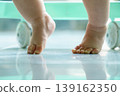 Close-up of a baby's hands and knees crawling on smooth tiled floor with green storage in background 139162350