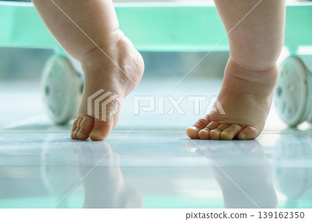 Close-up of a baby's hands and knees crawling on smooth tiled floor with green storage in background Close-up of a baby's hands and knees crawling on smooth tiled floor with green storage in background 139162350