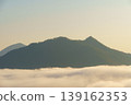Serene mountain landscape with rolling hills covered in dense green forest and misty clouds at sunrise or sunset sky 139162353