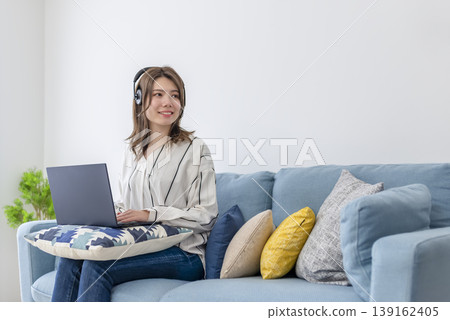 A woman working from home in her living room wearing a headset. A woman working from home in her living room wearing a headset. 139162405