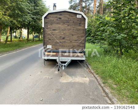 Mobile wooden sauna on a trailer parked on the side of the road, portable outdoor bathhouse in a forest area Mobile wooden sauna on a trailer parked on the side of the road, portable outdoor bathhouse in a forest area 139162548