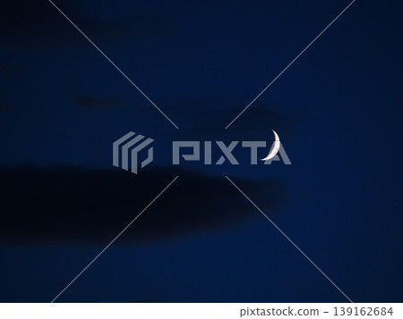 一輪彎月懸掛在暮色的天空。 一輪彎月懸掛在暮色的天空。 139162684