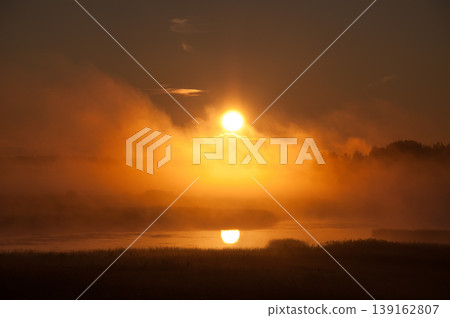 Rising sun behind the early morning fog in the Kokemaenjoki river delta in Pori, Finland Rising sun behind the early morning fog in the Kokemaenjoki river delta in Pori, Finland 139162807