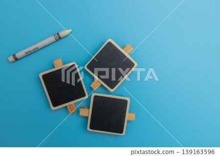 三塊迷你黑板和白色蠟筆整齊地排列在藍色背景前,旁邊留有空白區域。 三塊迷你黑板和白色蠟筆整齊地排列在藍色背景前,旁邊留有空白區域。 139163596