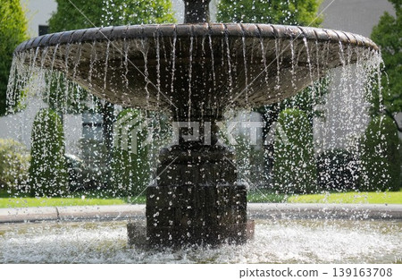 The fountain's spray, sparkling in the summer sun, and the classic beauty of its stonework. 139163708