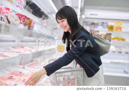 A businesswoman choosing meat at a supermarket. 139163718