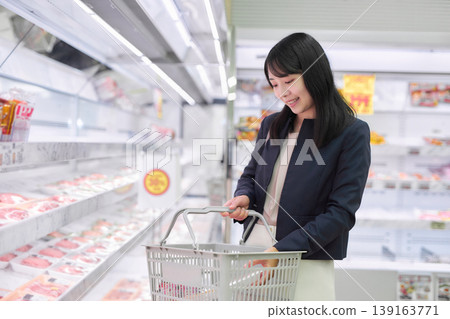 A businesswoman choosing meat at a supermarket. 139163771