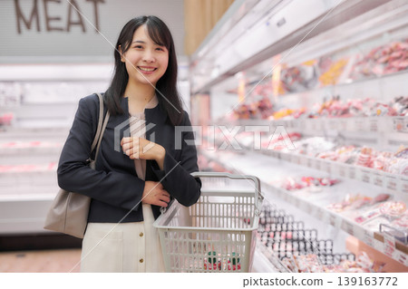 A businesswoman choosing meat at a supermarket. 139163772