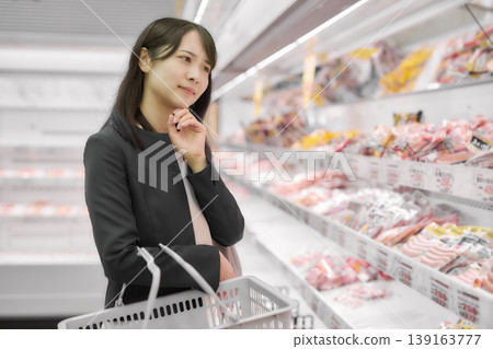 A businesswoman choosing meat at a supermarket. 139163777