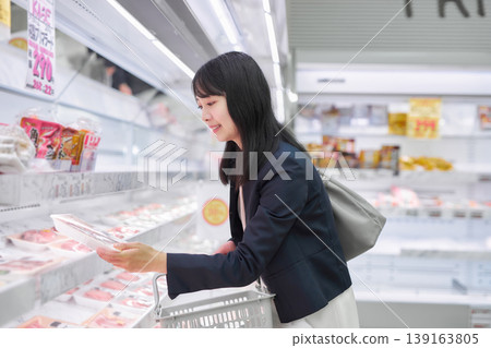 A businesswoman choosing meat at a supermarket. A businesswoman choosing meat at a supermarket. 139163805