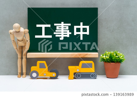 一塊寫著「施工中」的黑板、建築設備和一個鞠躬的人體模型。 139163989