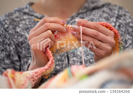 A woman's hands and the details of her handiwork as she crochets colorful yarn. A woman's hands and the details of her handiwork as she crochets colorful yarn. 139164208