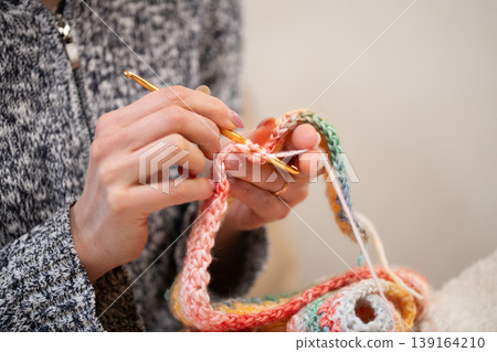 A woman's hands and the details of her handiwork as she crochets colorful yarn. A woman's hands and the details of her handiwork as she crochets colorful yarn. 139164210