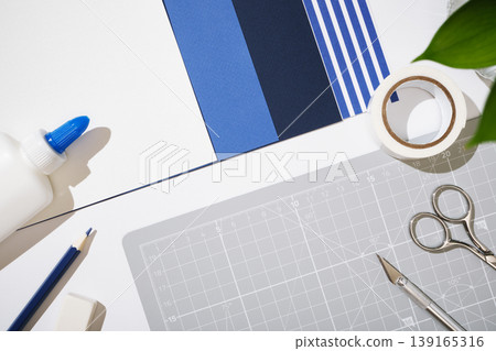 Top view of crafting tools on a grey cutting mat with blue paper samples. Copyspace Top view of crafting tools on a grey cutting mat with blue paper samples. Copyspace 139165316