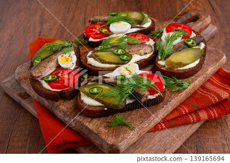 open sandwiches with sprats, vegetables and herbs, on a wooden board, breakfast, snack, open sandwiches with sprats, vegetables and herbs, on a wooden board, breakfast, snack, 139165694