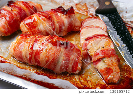baked chicken breast, wrapped in bacon, on a baking tray. in the home kitchen.close-up. baked chicken breast, wrapped in bacon, on a baking tray. in the home kitchen.close-up. 139165712